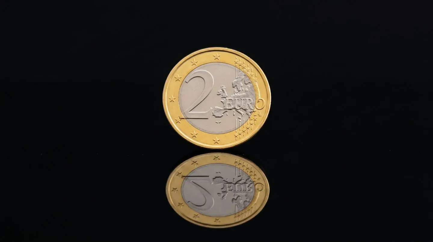 Gros plan sur une pièce de 2 euros posée sur une surface réfléchissante, symbolisant la libre circulation des petits montants.